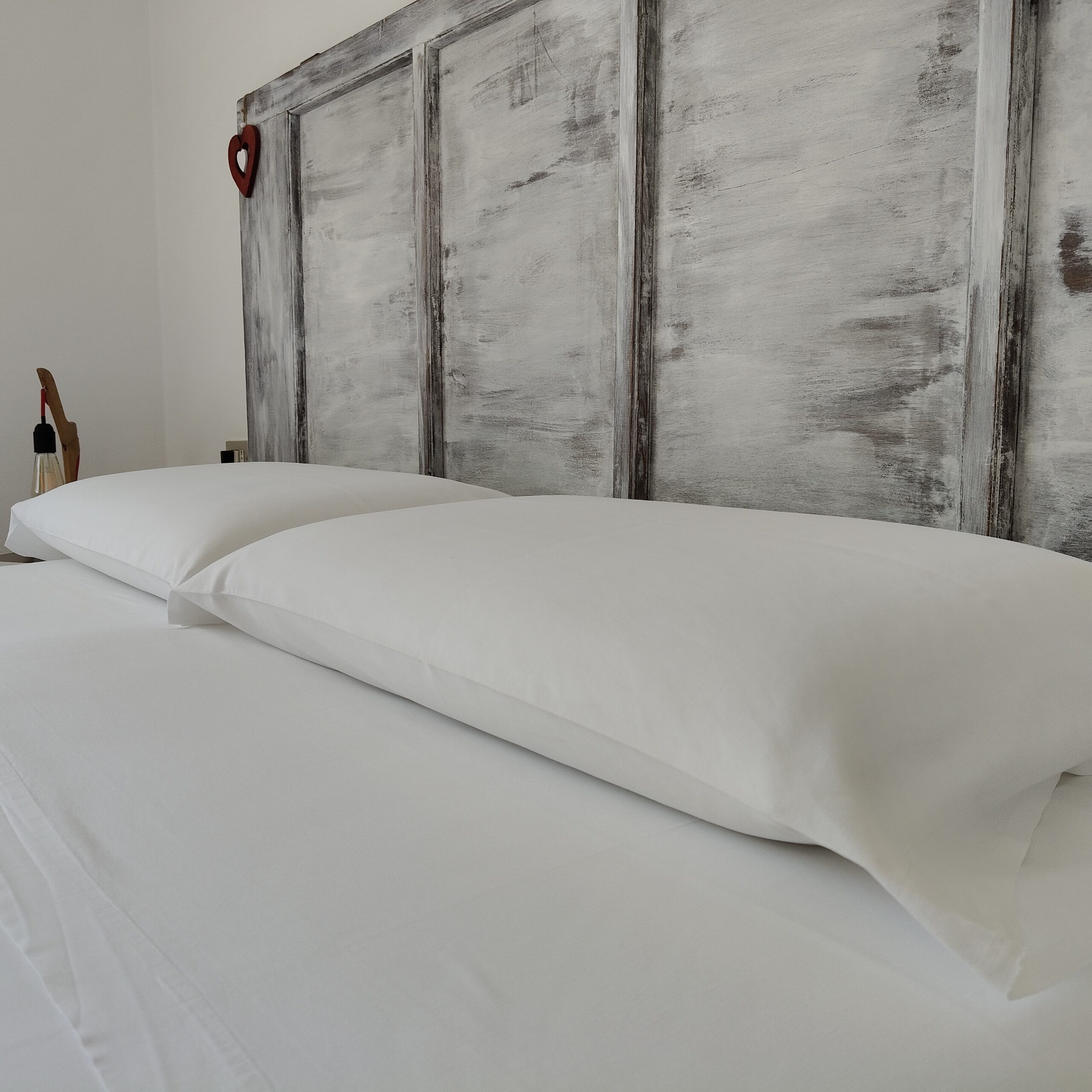 Cuscini con federe bianchissime su un letto ordinato in Sweetheart Apartment